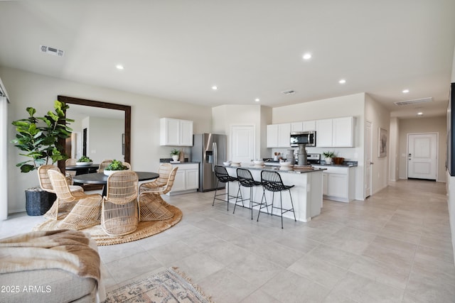 kitchen featuring stainless steel appliances, a breakfast bar area, visible vents, and white cabinets