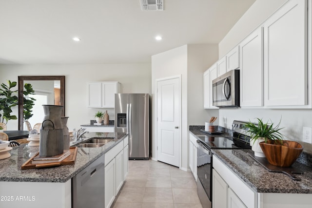 kitchen featuring visible vents, white cabinets, dark stone countertops, stainless steel appliances, and a sink