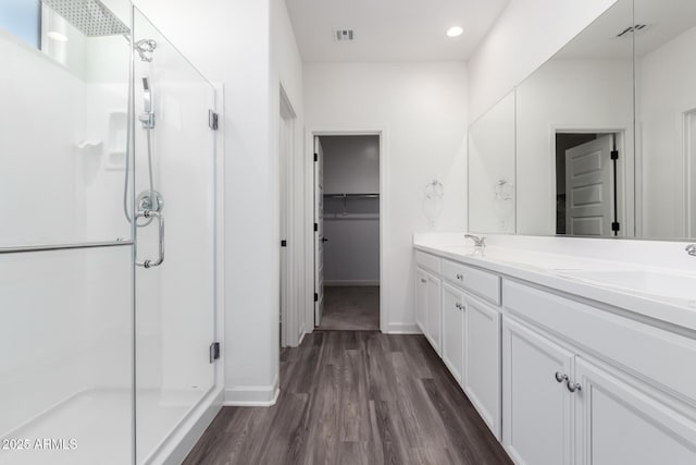 bathroom with a shower with shower door, vanity, and wood-type flooring