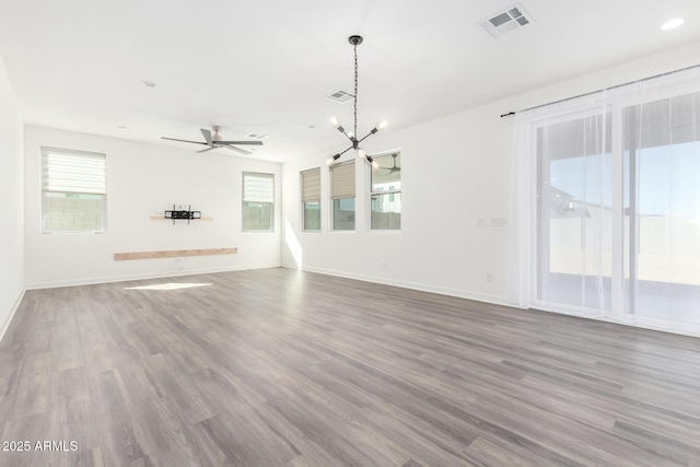 unfurnished living room featuring ceiling fan with notable chandelier and hardwood / wood-style floors