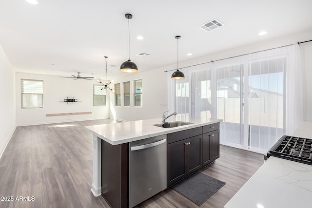 kitchen featuring dark hardwood / wood-style floors, decorative light fixtures, dishwasher, light stone countertops, and sink