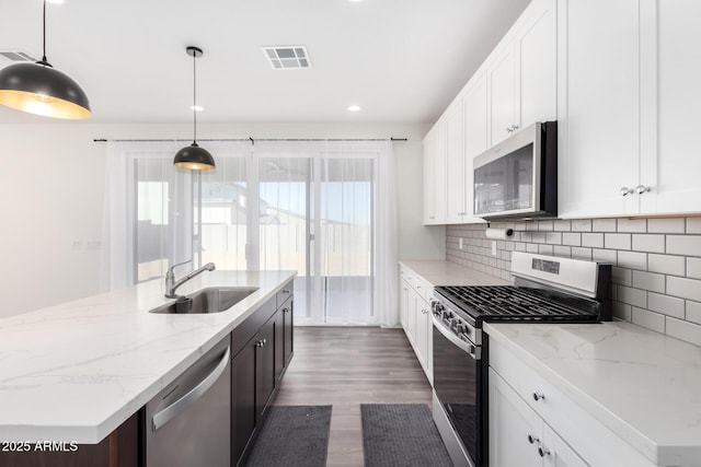 kitchen with decorative light fixtures, backsplash, sink, appliances with stainless steel finishes, and white cabinets