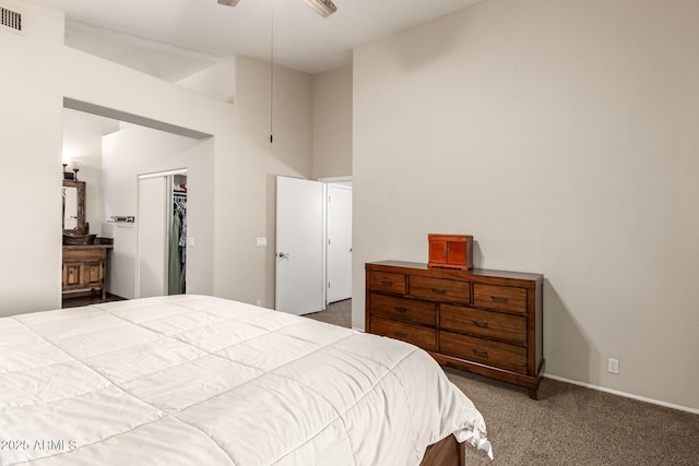 carpeted bedroom with a ceiling fan, a high ceiling, visible vents, and a walk in closet