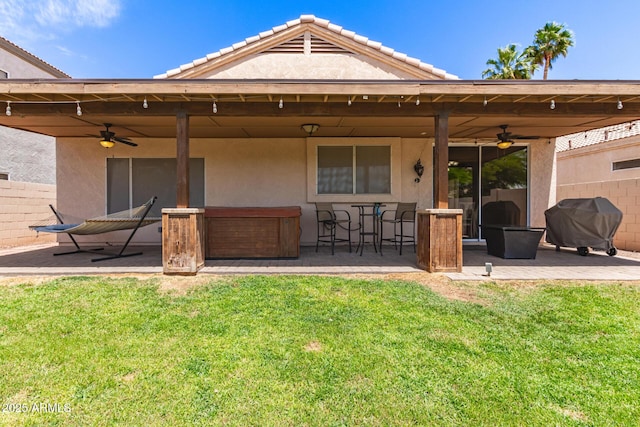 back of property featuring a patio, ceiling fan, stucco siding, and a yard