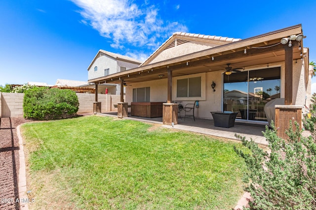 rear view of property featuring a yard, a ceiling fan, a patio area, and stucco siding