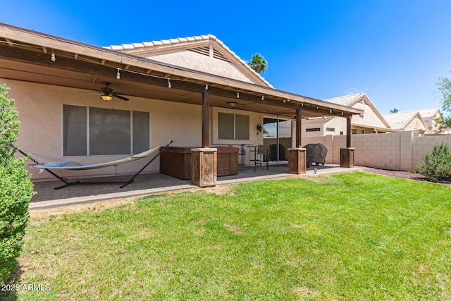 back of property with fence, stucco siding, a ceiling fan, a patio area, and a yard