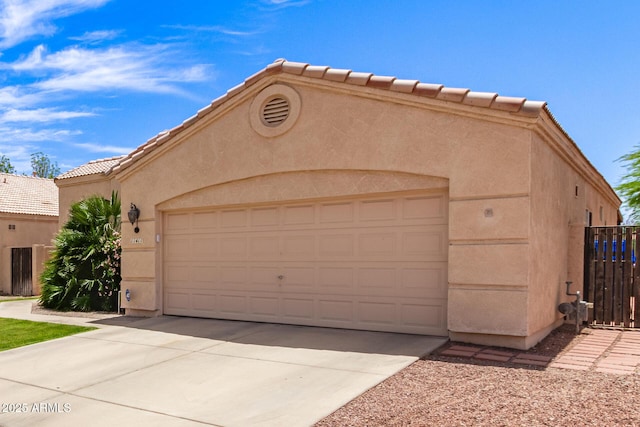 view of front of property with a garage, stucco siding, concrete driveway, and a tiled roof
