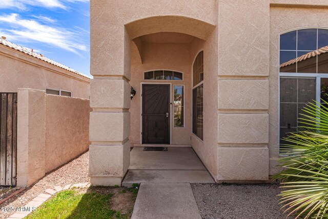 entrance to property with fence and stucco siding