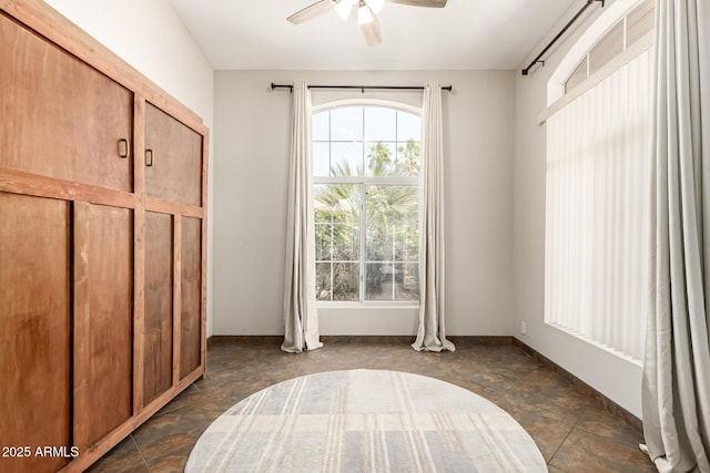 interior space featuring baseboards, a ceiling fan, and stone finish floor