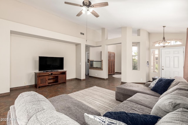 living area with baseboards, a ceiling fan, and visible vents