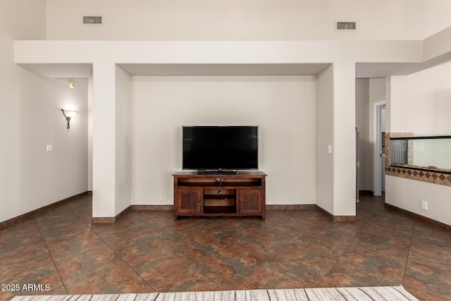 unfurnished living room featuring stone finish flooring, baseboards, and visible vents