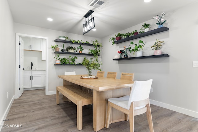 dining room featuring light wood-style floors, visible vents, and baseboards