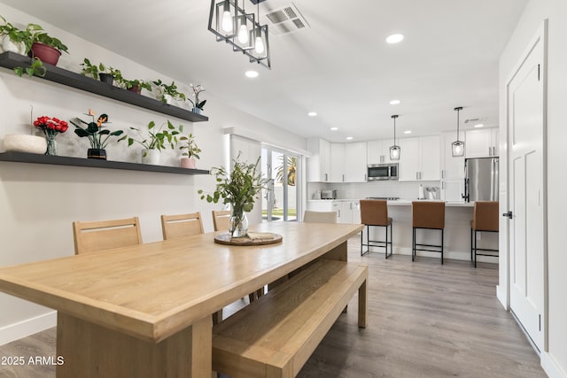 dining area featuring light wood finished floors, baseboards, visible vents, and recessed lighting