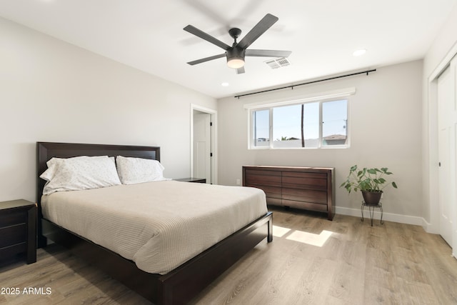 bedroom with a ceiling fan, light wood-style flooring, visible vents, and baseboards