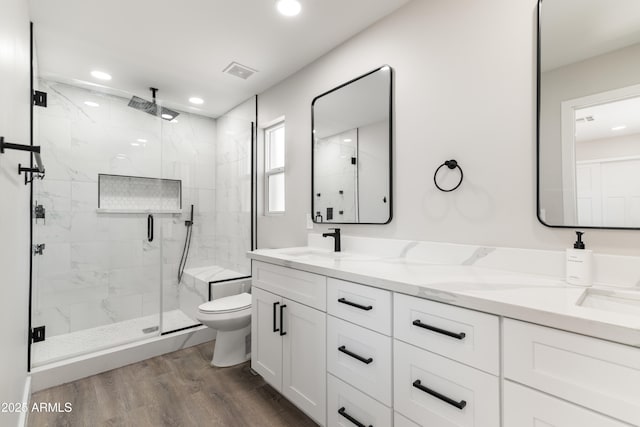 full bathroom featuring toilet, a sink, wood finished floors, visible vents, and a marble finish shower