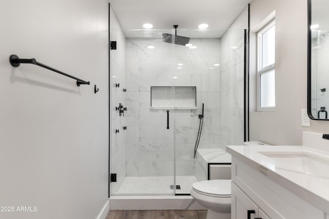 full bath featuring toilet, vanity, a marble finish shower, and wood finished floors