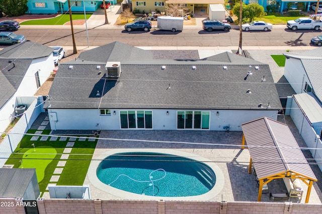 view of swimming pool with a residential view, central AC, and a fenced backyard
