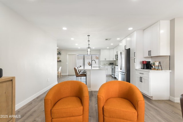 kitchen featuring stainless steel appliances, light countertops, white cabinetry, a sink, and an island with sink