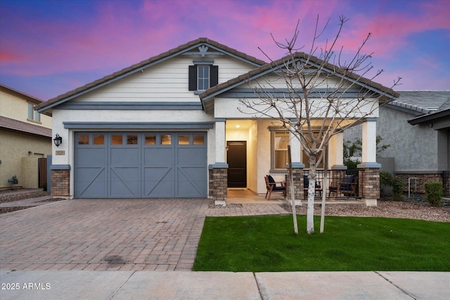 view of front facade featuring decorative driveway, a tile roof, a front lawn, and stucco siding