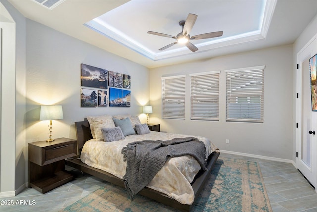 bedroom with ceiling fan, baseboards, and a tray ceiling