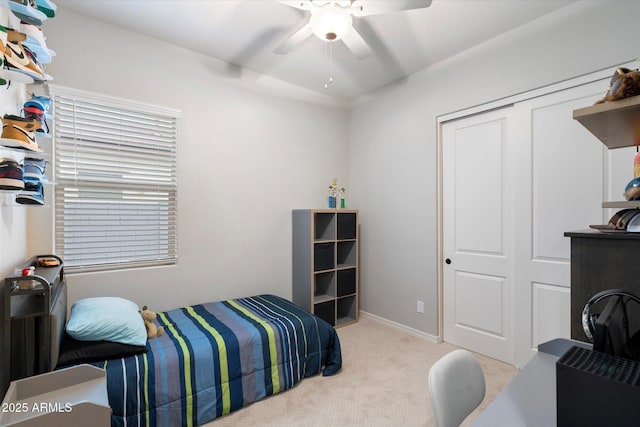 carpeted bedroom featuring a ceiling fan, a closet, and baseboards