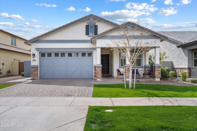 view of front of house featuring a front lawn, a tile roof, covered porch, stucco siding, and decorative driveway