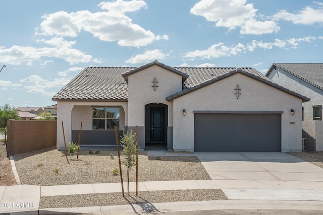 mediterranean / spanish house with an attached garage, a tiled roof, concrete driveway, and stucco siding