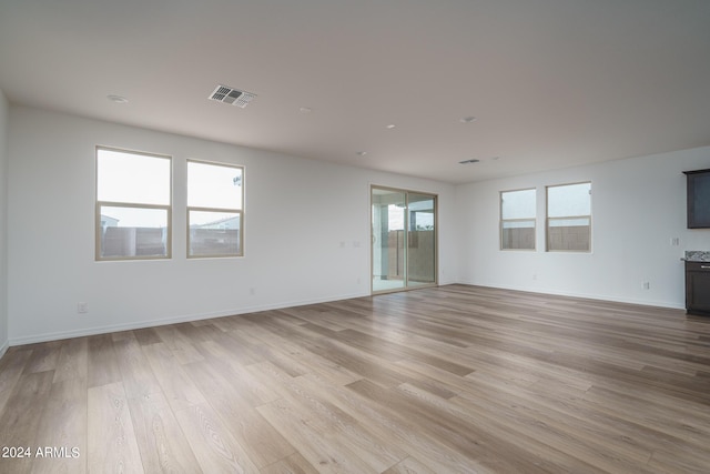 unfurnished living room with light wood-style flooring, visible vents, and baseboards