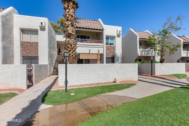 view of front of property with stairway, a gate, stucco siding, a fenced front yard, and a tile roof