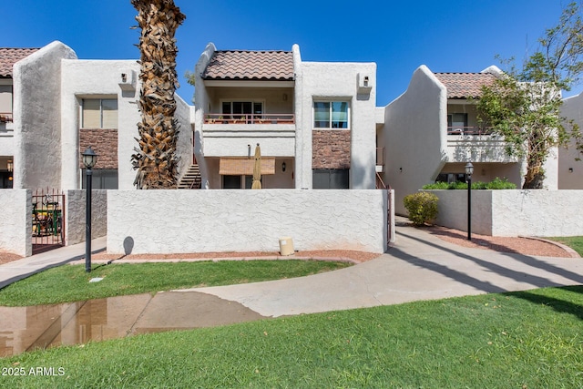 view of front of property featuring a tile roof, a gate, a fenced front yard, and stucco siding