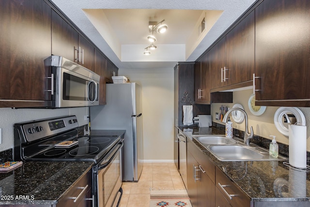 kitchen with light tile patterned floors, a sink, stainless steel appliances, dark brown cabinetry, and a raised ceiling