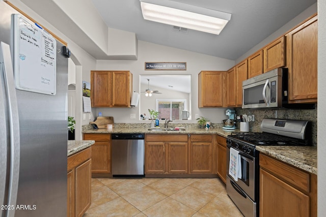 3905 E Derringer Way, Gilbert, AZ 85297 - kitchen with stainless steel appliances, lofted ceiling, light tile patterned flooring, brown cabinetry, and light stone countertops