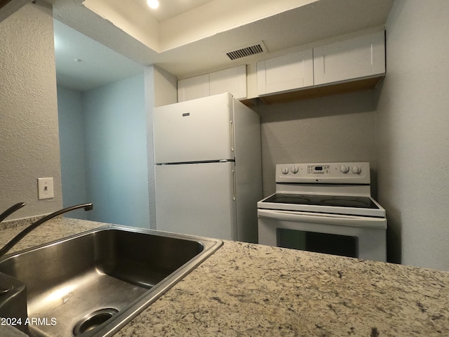 kitchen featuring range with electric cooktop, white refrigerator, a tray ceiling, white cabinetry, and sink