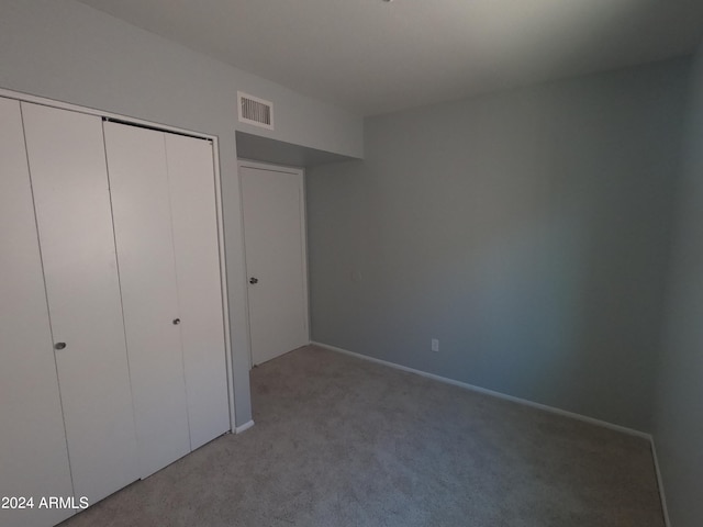 unfurnished bedroom with light colored carpet and a closet