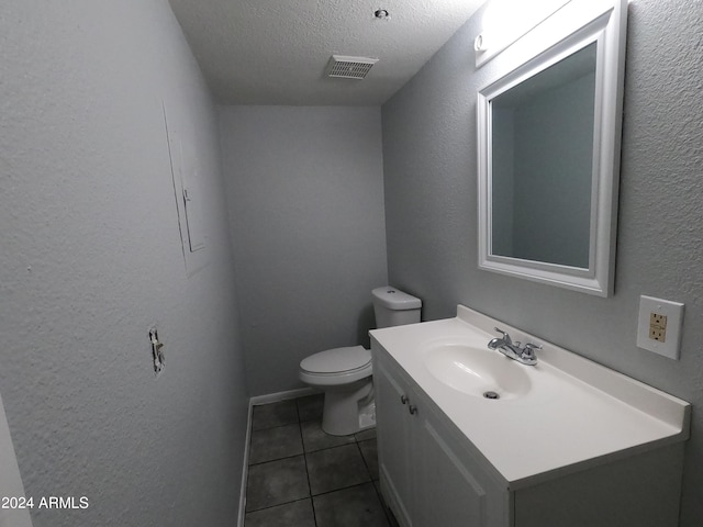 bathroom with tile patterned flooring, toilet, a textured ceiling, and vanity