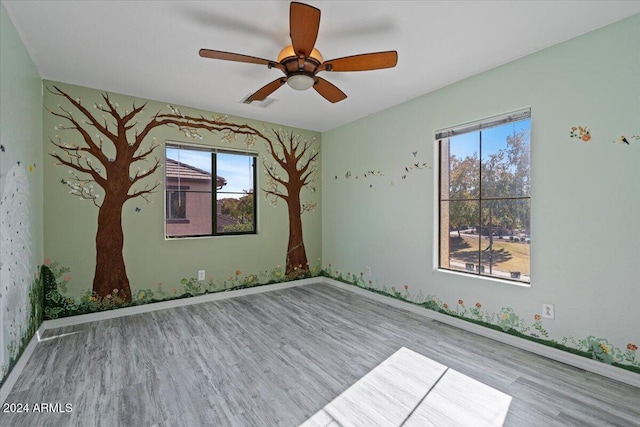 spare room featuring ceiling fan, a healthy amount of sunlight, and light hardwood / wood-style floors