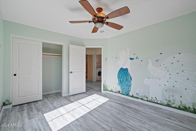 unfurnished bedroom with light wood-type flooring, ceiling fan, a closet, and washer / clothes dryer