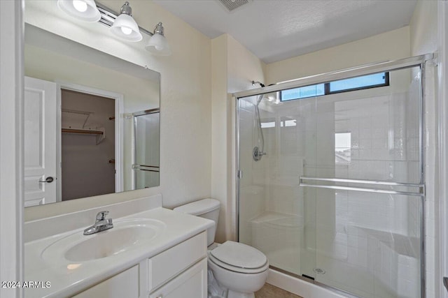 bathroom featuring walk in shower, vanity, toilet, and a textured ceiling