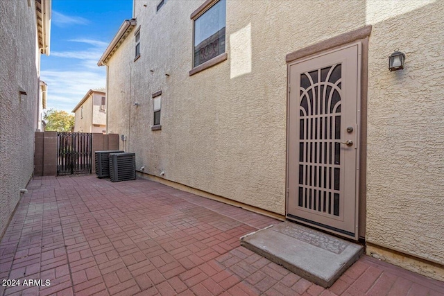 view of exterior entry featuring central AC unit and a patio