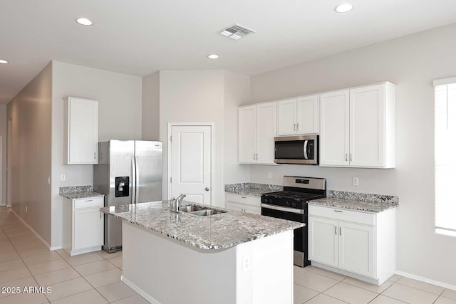 kitchen with a sink, light tile patterned floors, stainless steel appliances, and white cabinetry