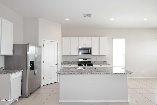 kitchen with visible vents, light stone countertops, white cabinets, stainless steel appliances, and light tile patterned flooring