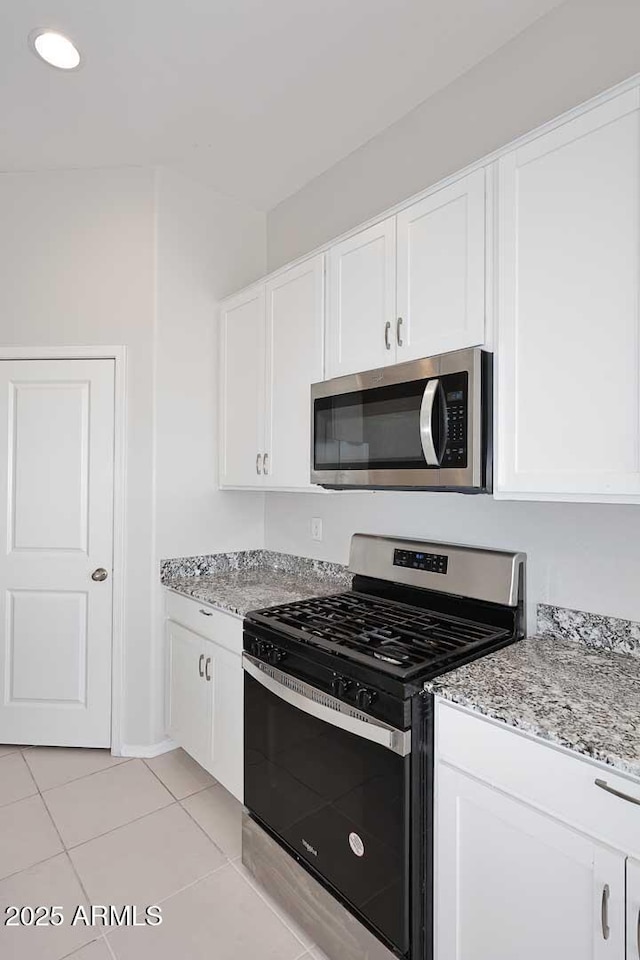 kitchen featuring light stone counters, appliances with stainless steel finishes, light tile patterned floors, and white cabinets
