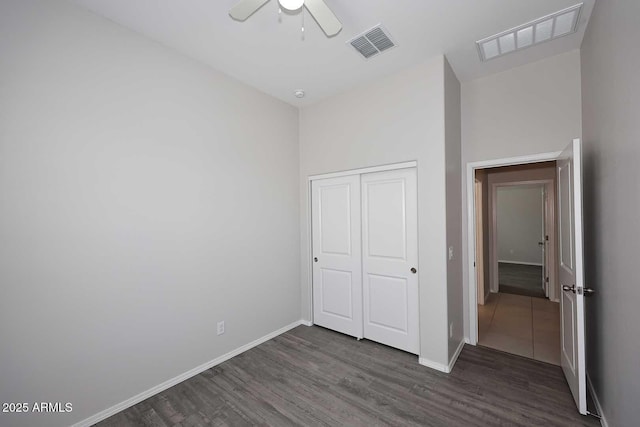 unfurnished bedroom with baseboards, a closet, wood finished floors, and visible vents