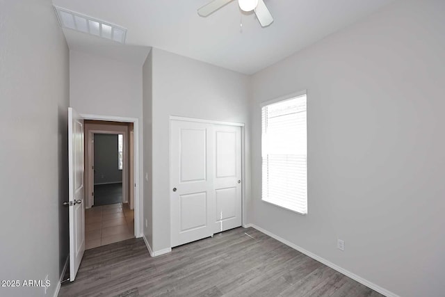 unfurnished bedroom with baseboards, a closet, wood finished floors, and visible vents