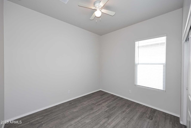 spare room with baseboards, ceiling fan, and dark wood-style flooring