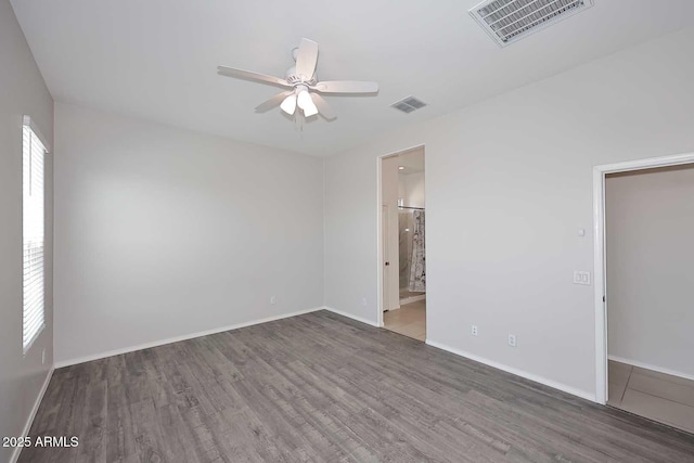 empty room with visible vents, ceiling fan, and wood finished floors