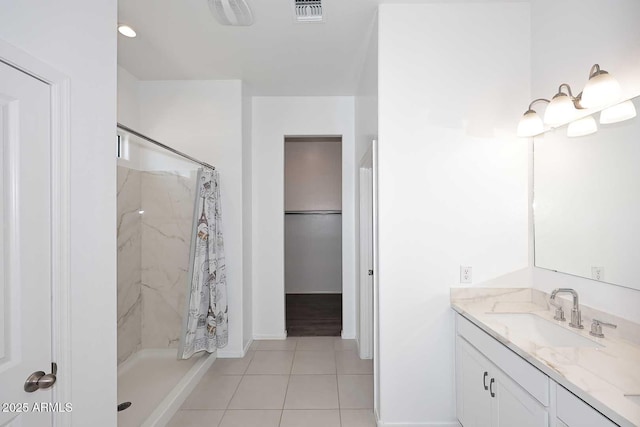 bathroom with a walk in closet, visible vents, a shower stall, vanity, and tile patterned floors