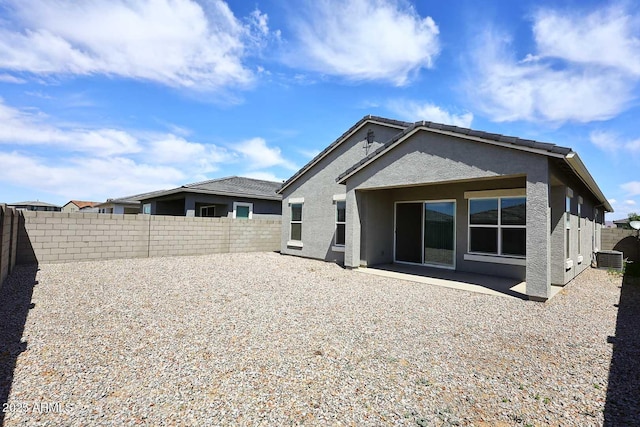 rear view of house with a fenced backyard, central AC unit, stucco siding, and a patio area