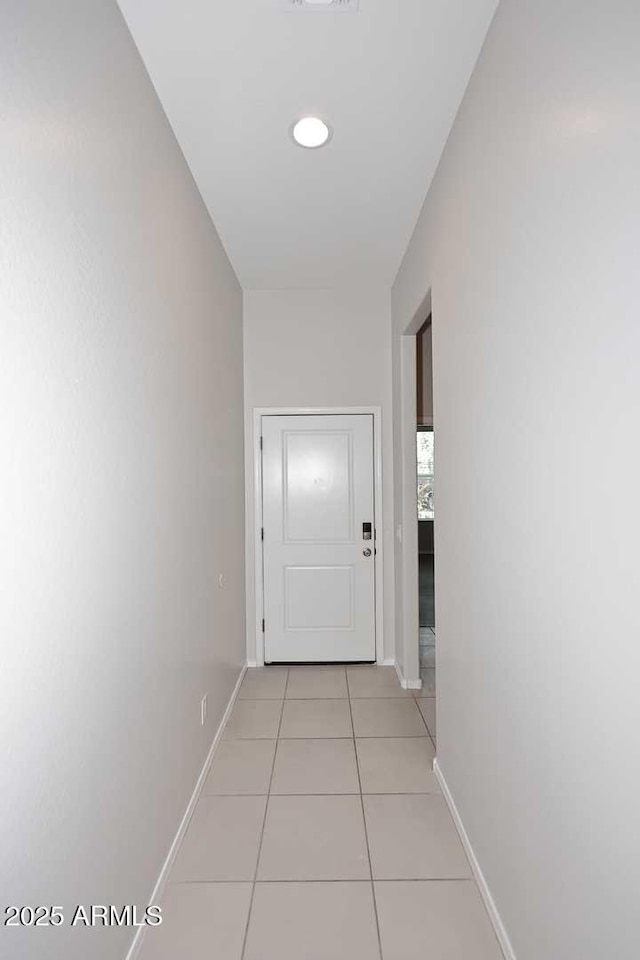 hallway with light tile patterned flooring, baseboards, and visible vents