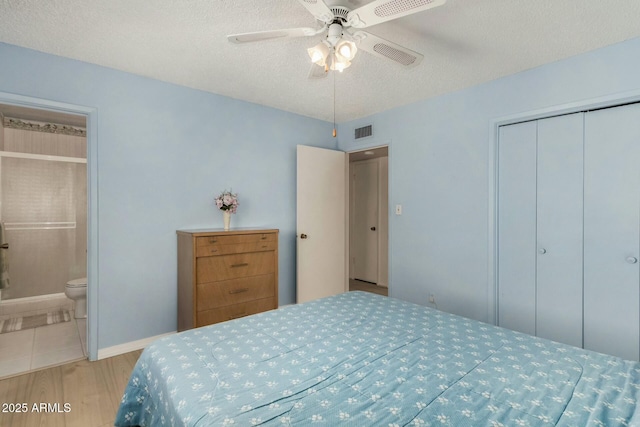 bedroom featuring visible vents, ensuite bath, wood finished floors, a textured ceiling, and a closet